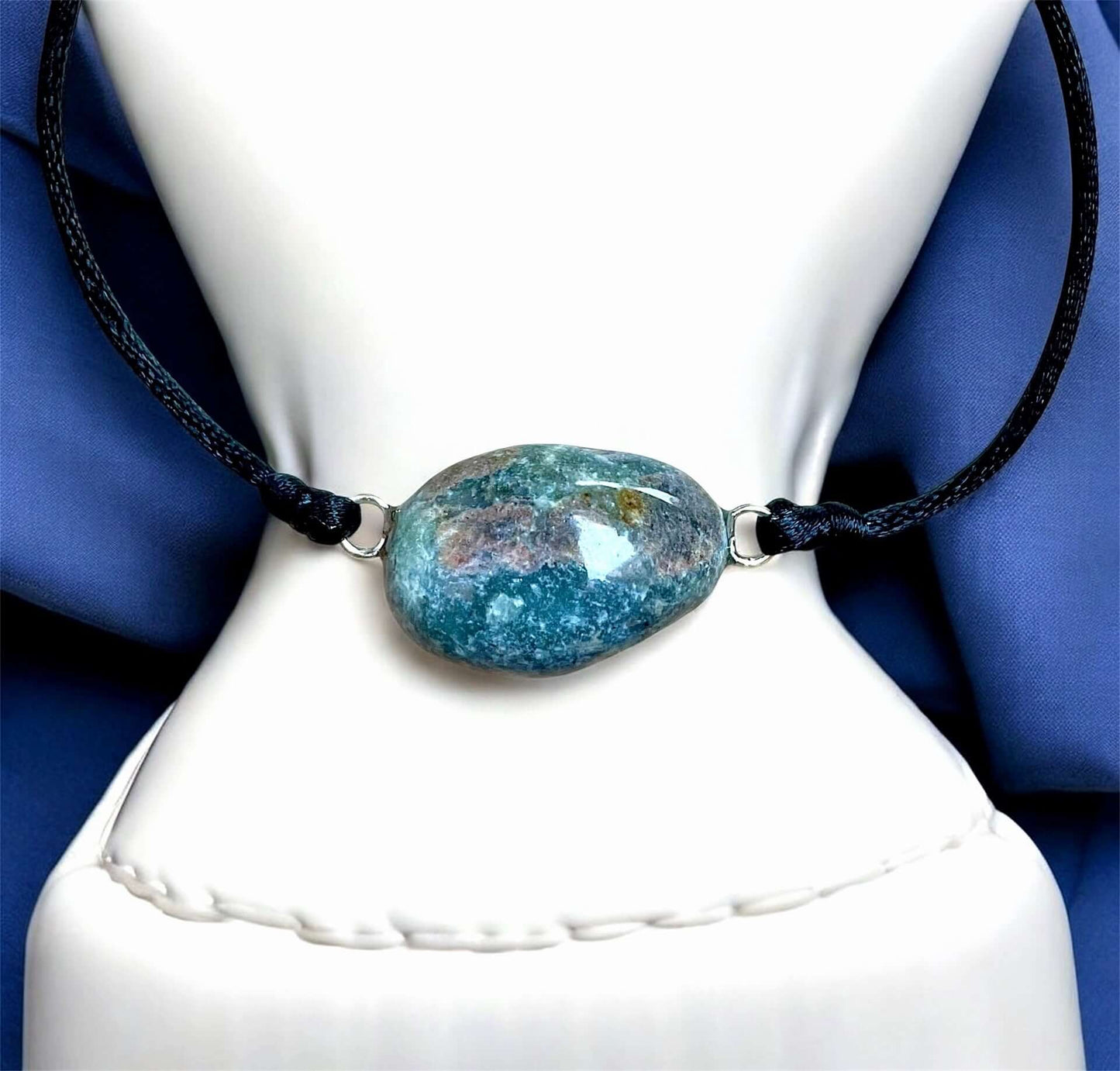 Collier Artigianale con Gemma Naturale dei Fiumi della Valsesia su sfondo blu, gioiello con gemma azzurra e nera.