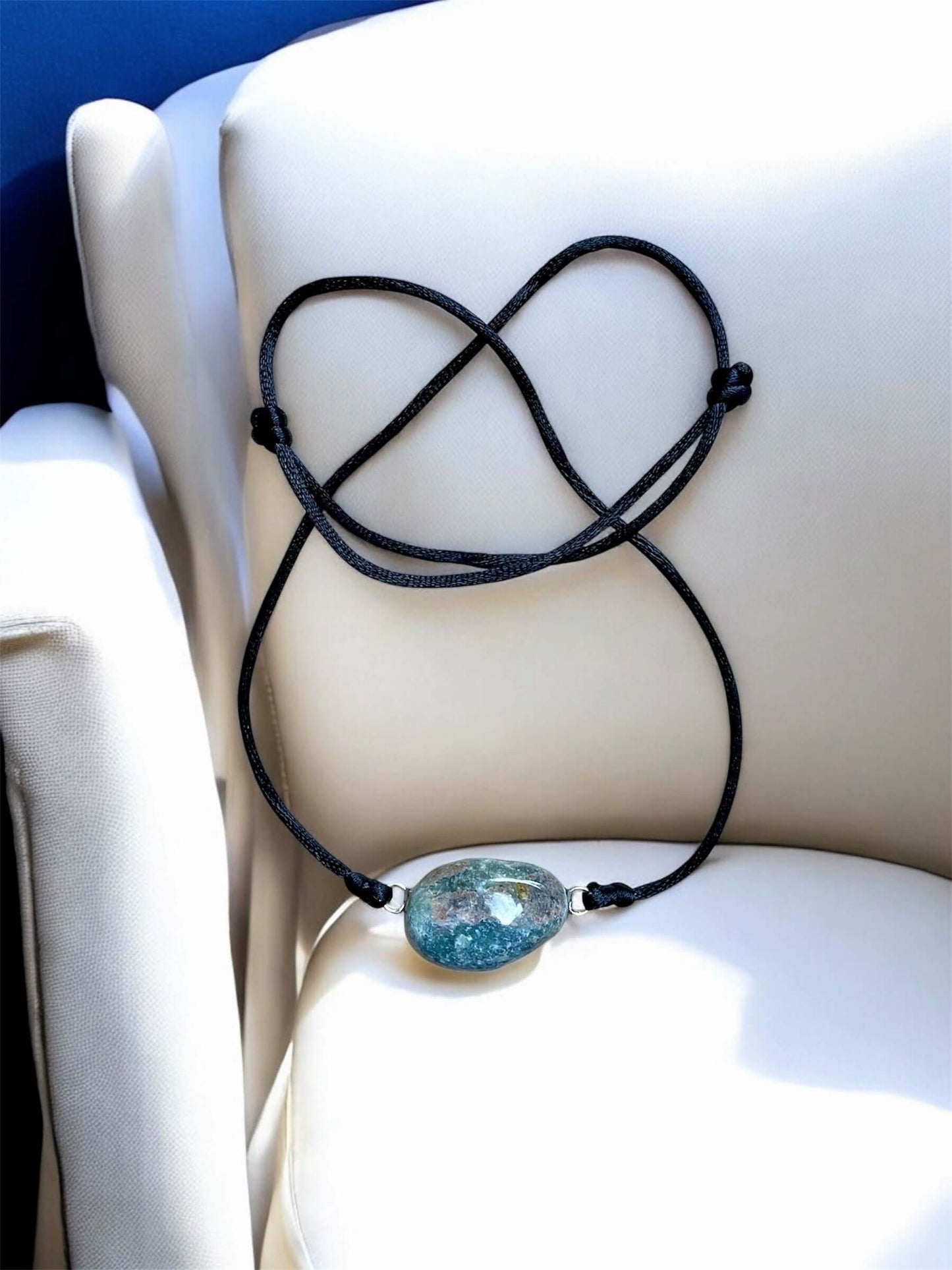 Collier Artigianale con Gemma Naturale dei Fiumi della Valsesia su un divano, evidenziando la bellezza della gemma e il design elegante.