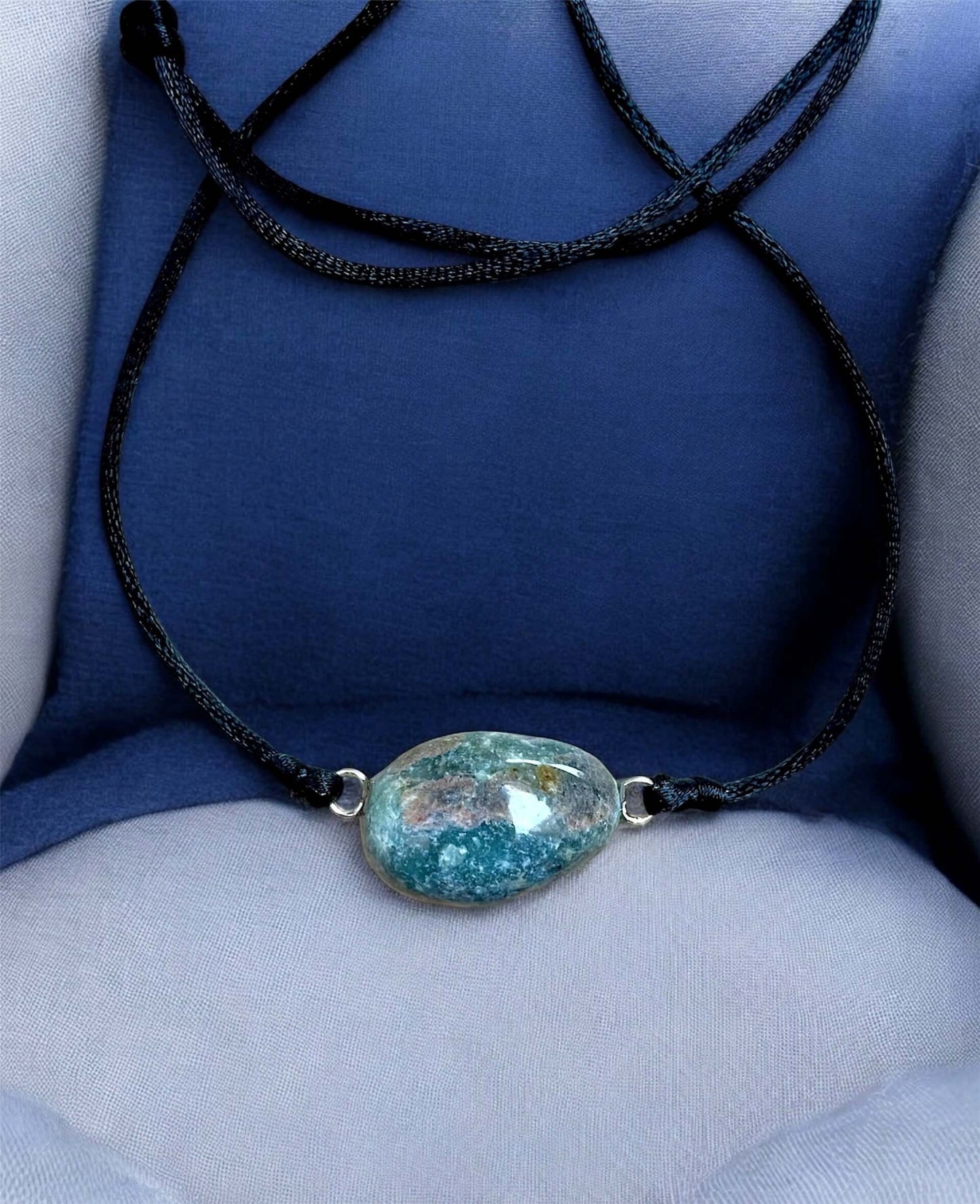 Collier Artigianale con Gemma Naturale dei Fiumi della Valsesia, caratterizzato da una gemma azzurra e blu, su sfondo blu elegante.