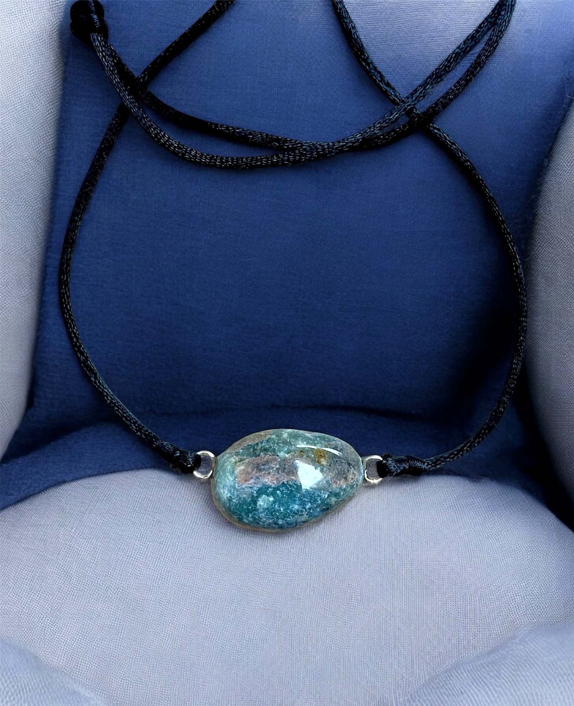Collier Artigianale con Gemma Naturale dei Fiumi della Valsesia, caratterizzato da una gemma azzurra e blu, su sfondo blu elegante.