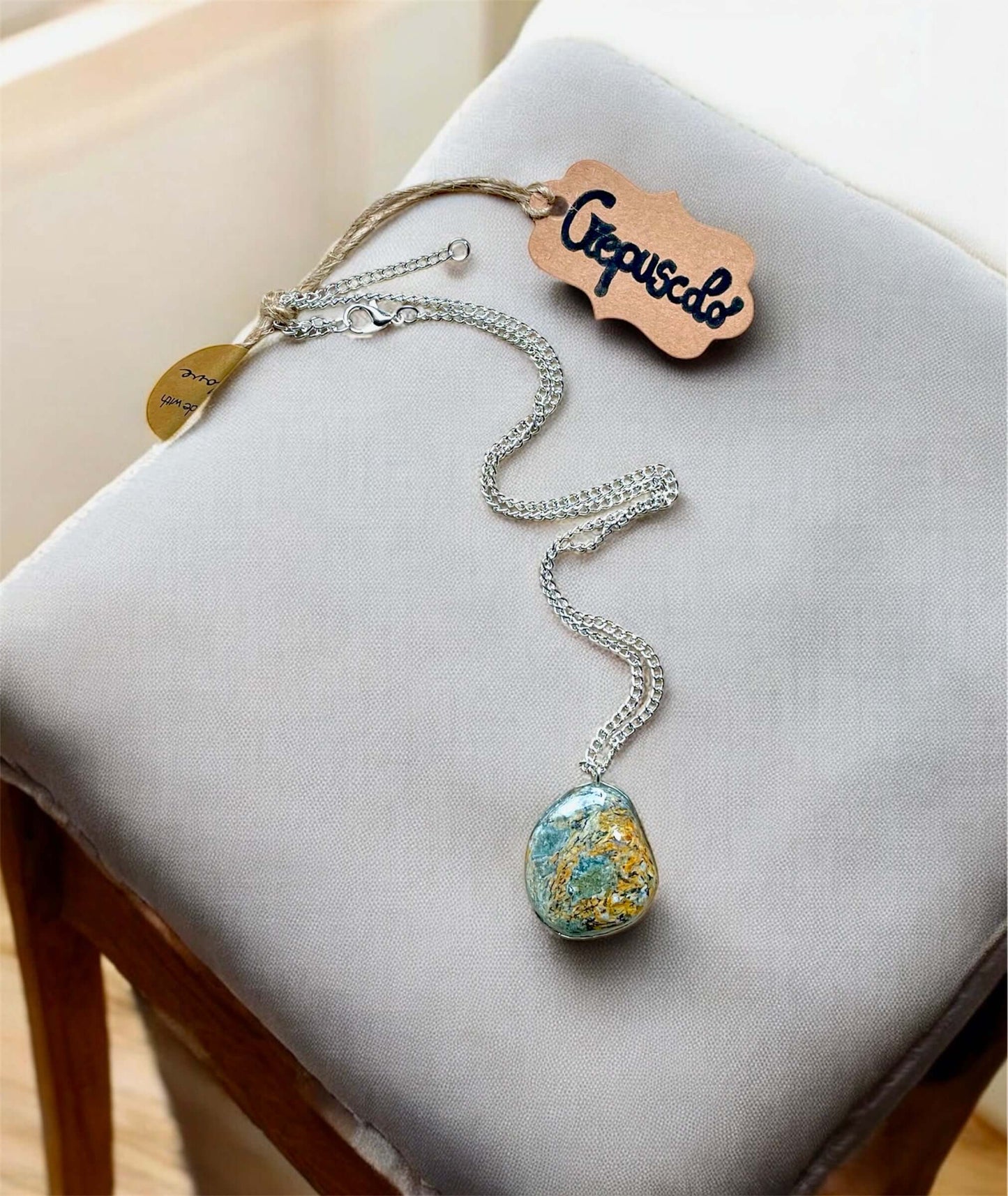 Collana Artigianale con Pietra Minerale Naturale dei Fiumi della Valsesia su un cuscino, con etichetta Crepuscolo.