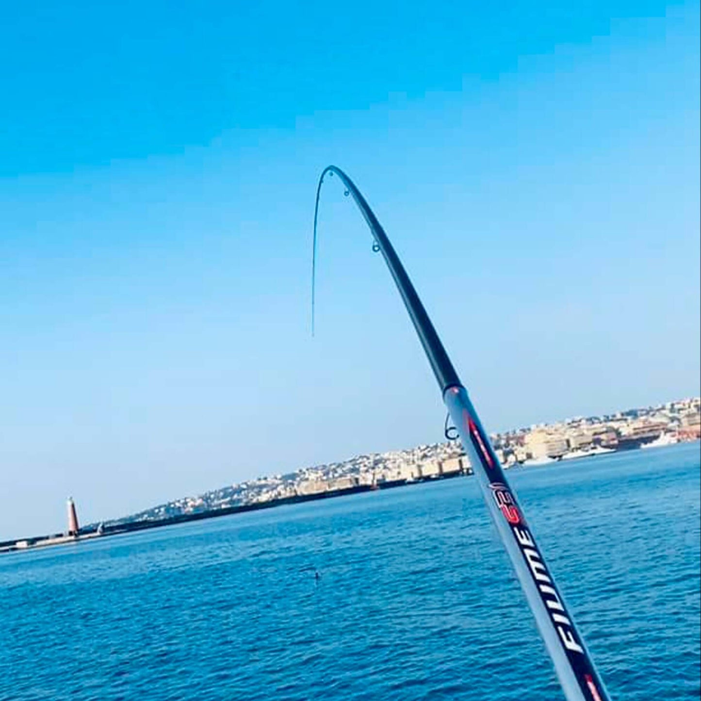 Canna da pesca Fiume S31 curva in azione sulla superficie dell'acqua, skyline sullo sfondo.