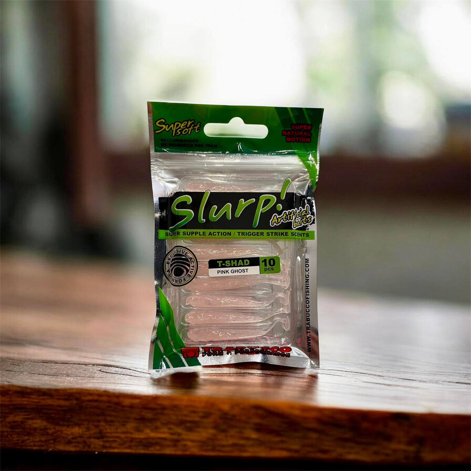 Trabucco Slurp Super Soft T-Shad Pink Ghost fishing bait package on a wooden surface.